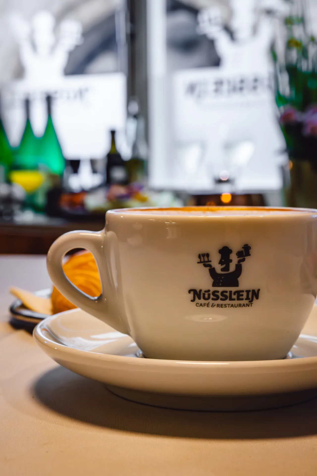 Cappuccino in a white cup with the Nüsslein logo at the café on the Krämerbrücke in Erfurt