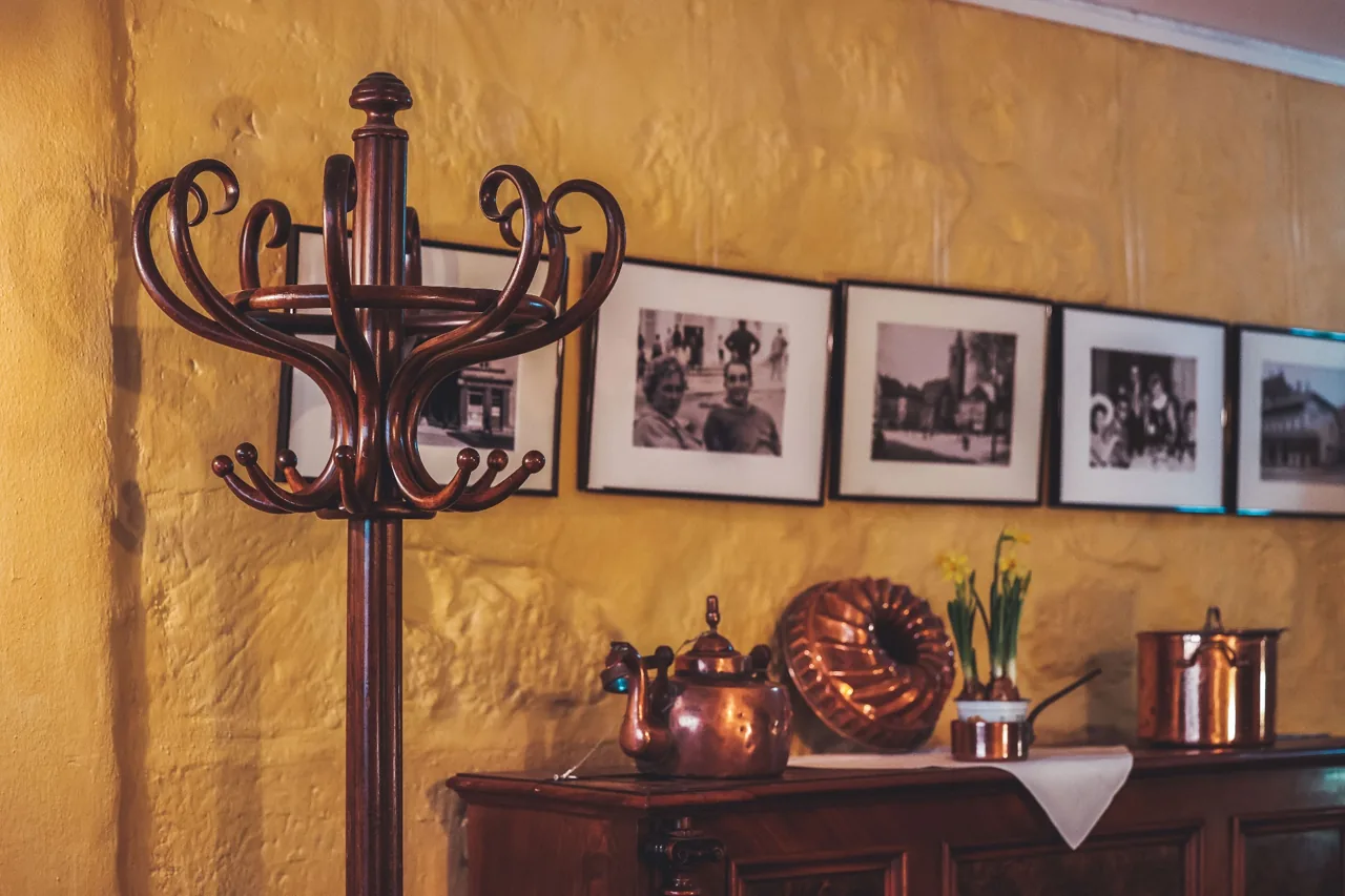 Historischer Garderobenständer und Wand mit alten Fotografien und Kupfergeschirr im Café Nüsslein Erfurt