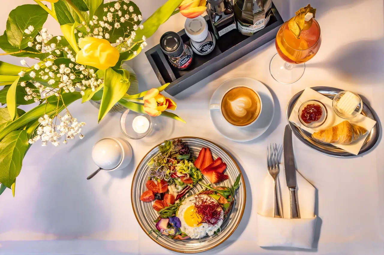 Frühstückstisch von oben mit Spiegelei-Teller, Cappuccino, Croissant und Tulpen im Café Nüsslein Erfurt